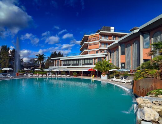 Hotel Terme Capasso view of the swimming pool with fountain and building in the background on a sunny day in Italy.