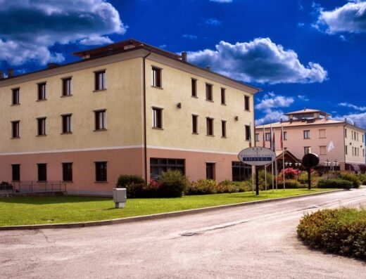 Hotel Tricolore: vista esterna dell'hotel con insegna, architettura moderna, cielo azzurro e verde curato. Ideale per viaggi e soggiorni.