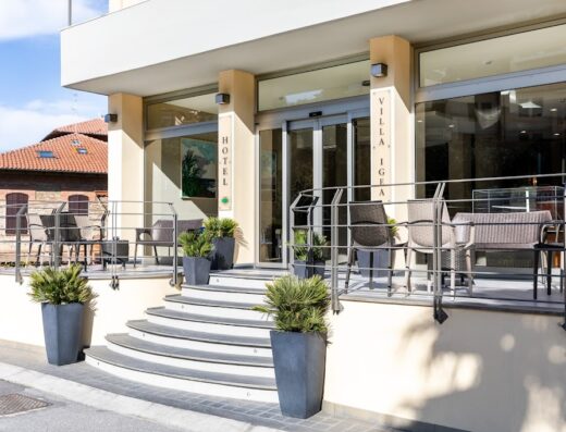 Ingresso principale dell'Hotel Villa Igea con gradini, vasi di piante ornamentali e tavolini esterni per gli ospiti.