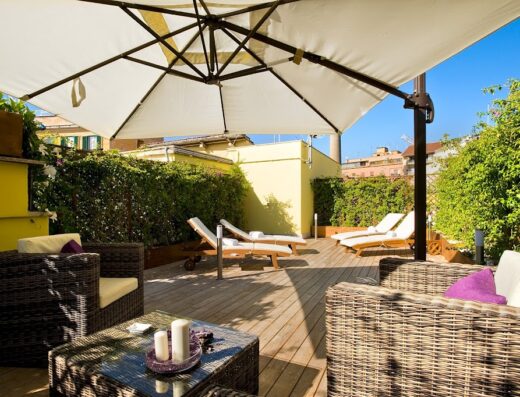 Terrazza solarium con ombrellone, lettini prendisole e divanetti in vimini all'Hotel Villa San Lorenzo Maria, per un soggiorno di relax