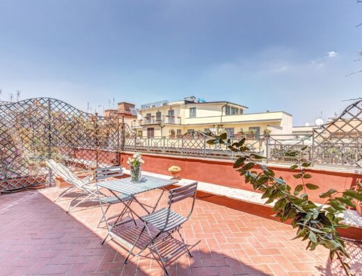 Terrace view at Hotel Villafranca Rome featuring outdoor seating, lounge chairs, and views of the surrounding buildings under a clear sky.
