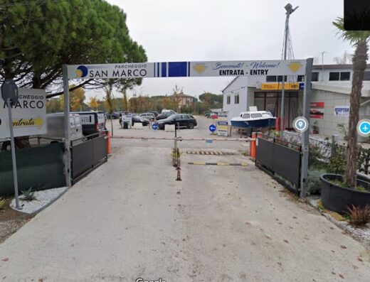 Ingresso del parcheggio San Marco a Venezia, con cartelli di benvenuto in italiano e inglese. Area di sosta per auto, moto e altri veicoli.