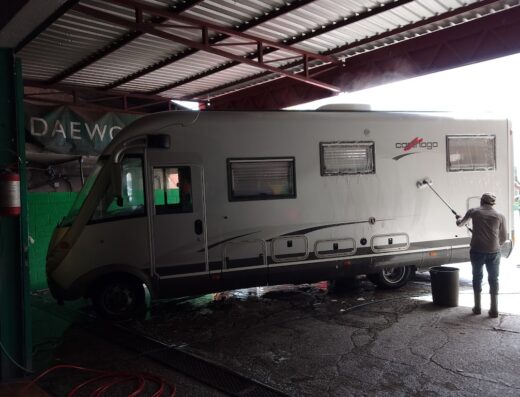 Un camper Cartago viene lavato in un autolavaggio, con operatore che usa una spazzola a manico lungo, ideale per viaggi e vacanze su strada.