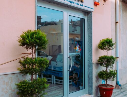 Ingresso dell'agenzia viaggi I Viaggi di Maia, con insegna luminosa e piante ornamentali in vaso. Servizi di viaggio personalizzati.