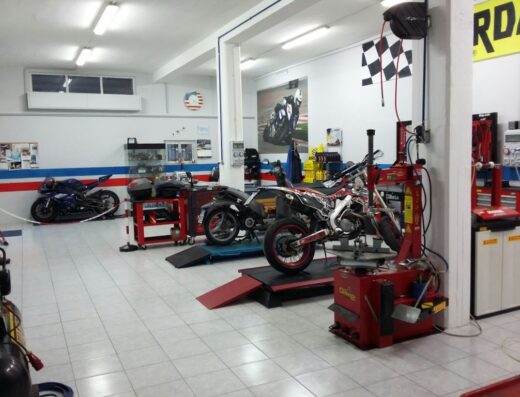 Interno di Iannone World Bike, officina specializzata in riparazione moto, accessori e vendita. Si vedono diverse moto, attrezzature per la manutenzione e poster di competizioni.