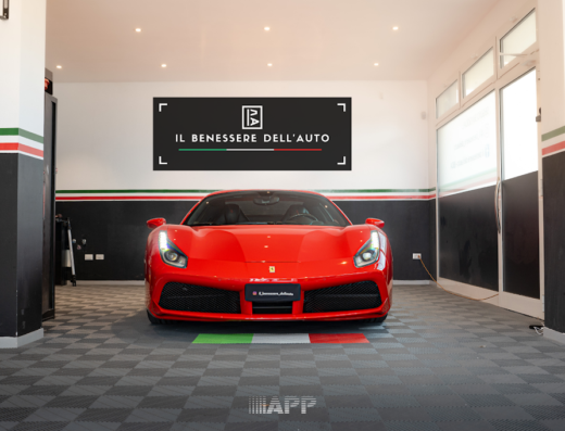 Una Ferrari rossa in un centro di detailing auto a Treviso, con logo 'Il Benessere dell'Auto', pavimento a scacchi e dettagli tricolore.