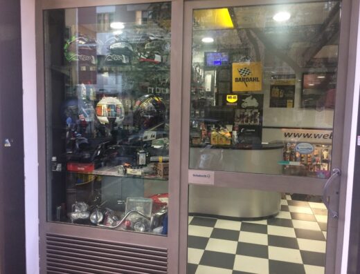 Vetrina del negozio Il Casco sas a Milano, con esposizione di caschi moto AGV, accessori e ricambi per motocicli, lubrificanti Bardahl e abbigliamento tecnico.