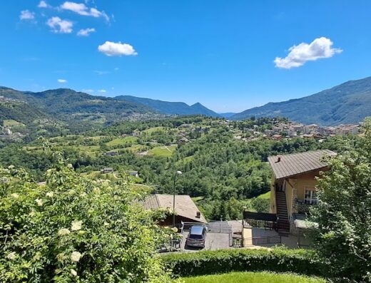 Vista panoramica mozzafiato dal Castello di Venere, Foresteria Lombarda, con montagne verdi, cielo azzurro e abitazioni tipiche. Un'oasi di relax e bellezza per viaggiatori e motociclisti.