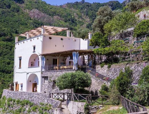 Il Cavaliere dei Conti Agriturismo: vista esterna della struttura bianca su una collina con terrazza panoramica e vegetazione rigogliosa.