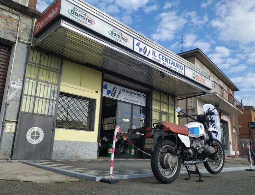 Il Centauro Moto: officina di riparazione e vendita accessori per moto, con una BMW d'epoca parcheggiata di fronte.