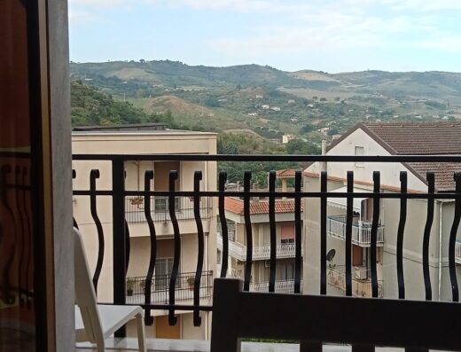 Una vista panoramica dalla finestra di Il Centro Short Lets, che mostra edifici e colline verdeggianti sotto un cielo nuvoloso.