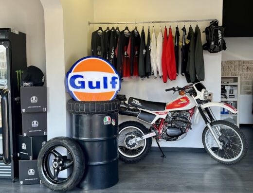 Interno del negozio Il Covo del Motociclista con moto Honda XL, abbigliamento tecnico, caschi e accessori moto in vendita e noleggio.
