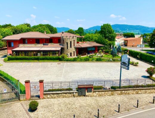 Il Leone d'Oro Hotel in Italy, featuring a unique tower structure, ample parking, and a welcoming restaurant, set against a backdrop of rolling hills.