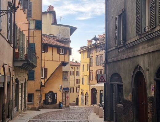 Strada acciottolata a Bergamo Alta, Italia, con edifici storici sui lati; perfetta per un viaggio in moto alla scoperta di borghi caratteristici.