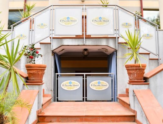 Ingresso principale di Il Piccolo Hotel accessibile tramite una scalinata decorata con piante in vaso e insegne del nome dell'hotel.