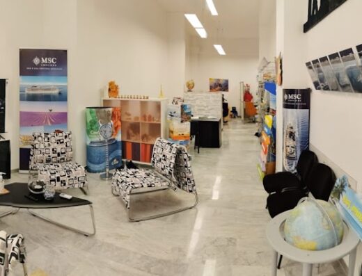 Interno di In Freedom Viaggi&Turismo, agenzia viaggi che offre servizi e marketplace per motociclisti e viaggiatori. Arredamento moderno, brochure MSC Crociere, sedute confortevoli.