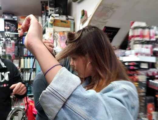 Ragazza che si arriccia i capelli in un negozio di accessori per capelli, usando un arricciacapelli elettrico.