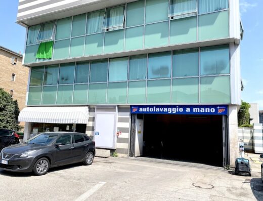 Veduta esterna di IP Autolavaggio a Mano, con auto parcheggiata davanti. Servizio di lavaggio auto e moto a mano.