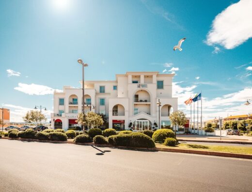 Jazz Hotel in Italy on a sunny day with a seagull flying overhead, showcasing its modern architecture and inviting atmosphere.