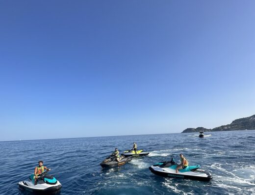 Noleggio moto d'acqua a Taormina Letojanni: Gruppo di persone che guidano moto d'acqua sul mare blu con cielo sereno, servizio di noleggio disponibile.