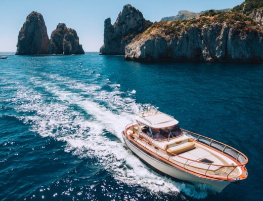 Motoscafo di lusso in navigazione nelle acque cristalline di Sorrento, con vista mozzafiato sui faraglioni. Servizi di noleggio barche e yacht disponibili.