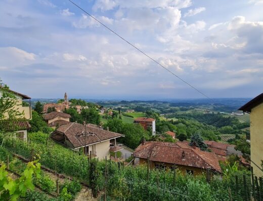 Paesaggio collinare italiano con case rurali e vigneti, ideale per viaggi in moto e scoperta del territorio.