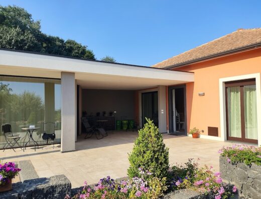 La Casa dell'Alloro: Vista esterna della casa vacanze con patio arredato, giardino fiorito e architettura moderna, ideale per un soggiorno rilassante.