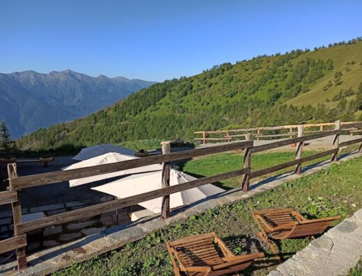 Vista panoramica a La Darbunera con sdraio in legno, ombrelloni bianchi e recinto di legno. Ideale per relax e viaggi in moto.