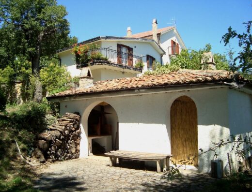 Casa di campagna italiana con barbecue esterno, legna da ardere e tetto in tegole, tipica architettura per un viaggio in moto alla scoperta della Dolce Vita.