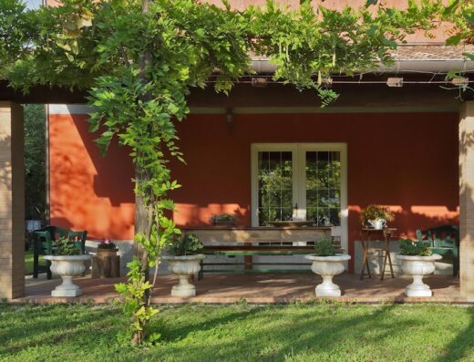 Veranda accogliente a La Fonte, con edera rampicante, vasi decorativi e arredi in legno, ideale per relax e convivialità all'aperto.