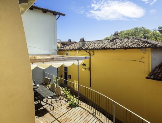 Vista panoramica dalla terrazza di La Giolitta Accomodations di Daniela Vacca, con tavolo, sedie e vista sui tetti di un borgo italiano.
