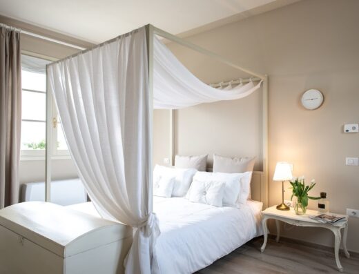 Lussuosa camera da letto con letto a baldacchino e biancheria bianca presso La Locanda di Corrado, ideale per un soggiorno rilassante e confortevole.