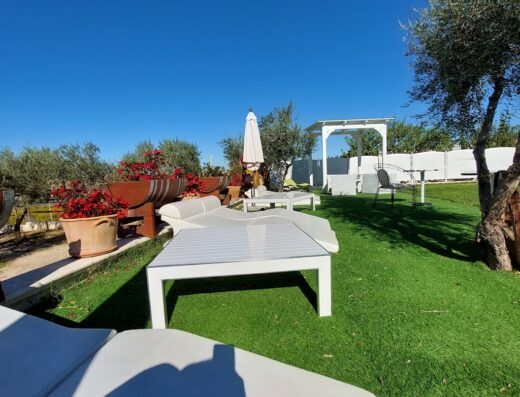 Esterno accogliente de La Locanda di Zì Nicola con lettini bianchi su prato verde, ombrellone e gazebo, ideale per relax e vacanze.
