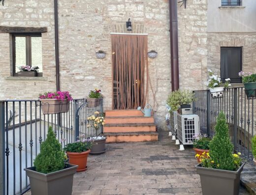 La Loggia di San Martino: Vista esterna della loggia con piante in vaso, fiori colorati e dettagli architettonici unici.