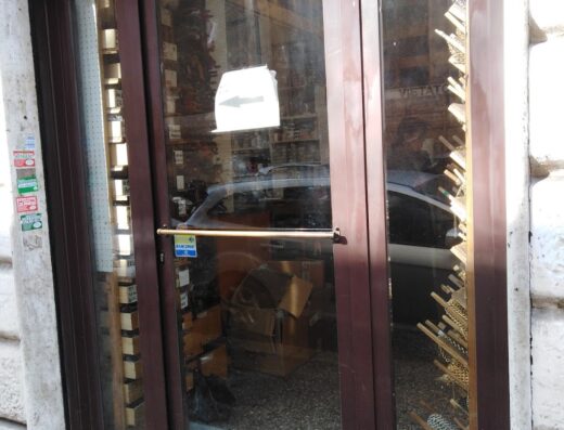 Vetrine del negozio La Nuova Testera con esposizione di accessori e ricambi per moto, con scaffali visibili attraverso il vetro.