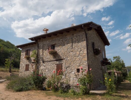 La Piana dei Castagni, agriturismo familiare: Facciata in pietra di un casale con fiori alle finestre, immerso nel verde.