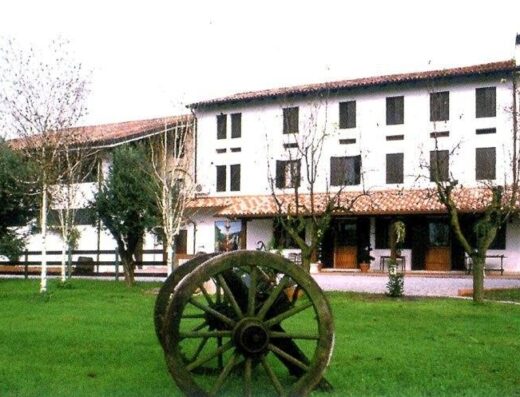 La Pioppa Agriturismo Sacile: vista esterna dell'agriturismo con un antico carro agricolo in primo piano, immerso nel verde della campagna veneta. Ideale per un soggiorno rilassante e una vacanza a contatto con la natura.