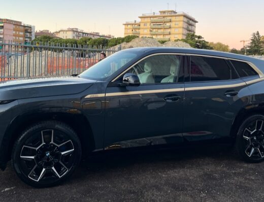 La Piramide Autolavaggio a Mano: SUV moderno di colore scuro con finiture dorate, parcheggiato in un contesto urbano con edifici sullo sfondo.