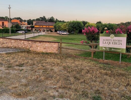 Ingresso dell'Agriturismo La Quercia con cartello benvenuto, alloggi, ristorante, cucina e parcheggio auto. Ideale per motociclisti in viaggio.