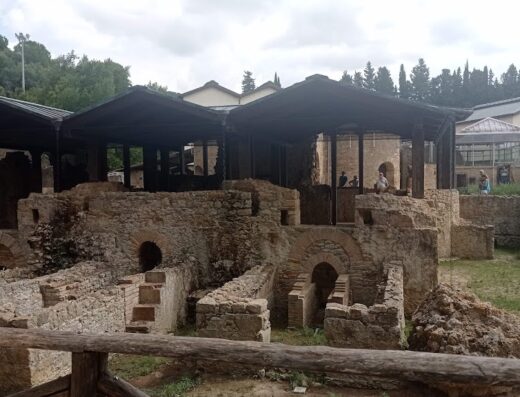 Le rovine antiche de La Regina di Saba, un sito archeologico con strutture in pietra e tettoie protettive, offrendo uno sguardo sulla storia antica.