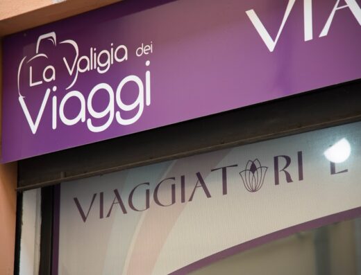 Insegna viola e bianca de "La Valigia dei Viaggi", agenzia viaggi e accessori per motociclisti e viaggiatori