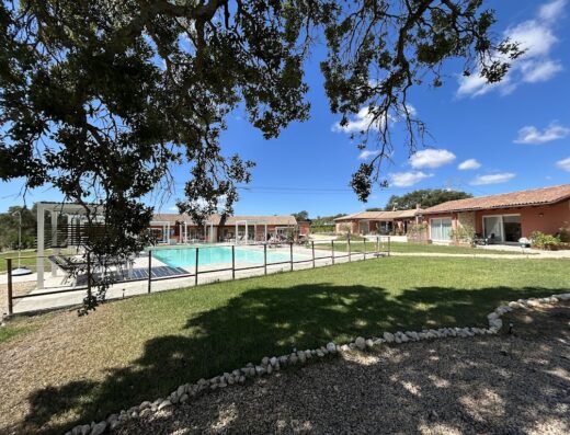 La Vinia Bed&Wine Experience: Vista della piscina e degli alloggi in stile rustico con cielo azzurro, ideale per un soggiorno rilassante.