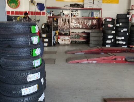 Lancia Bruno & Figli SNC Driver Center Pirelli Avezzano: Interno dell'officina con pneumatici nuovi, ponte sollevatore e insegna Michelin.