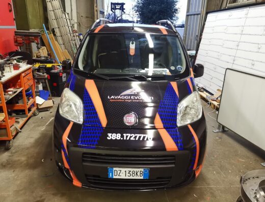 Fiat Fiorino personalizzata con grafica "Lavaggi Evoluti" per servizi di pulizia interni auto, visibile numero di telefono per contatto.