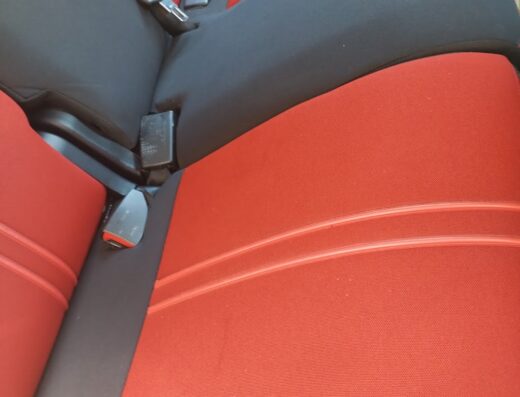 Dettaglio degli interni auto a Pavia dopo il lavaggio professionale da Axel, con sedili in tessuto rosso e nero e cinture di sicurezza.