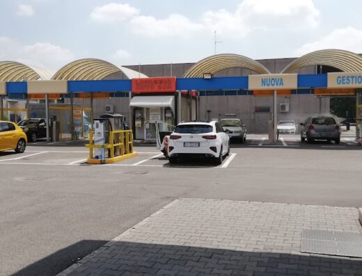 Lavaggio Auto La Grumellina: View of the car wash area with several cars parked in the bays, including a yellow Peugeot and a white Kia. The facility offers a self-service car wash.