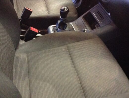 Interni auto con sedili in tessuto grigio che mostrano segni di usura prima del lavaggio professionale della tappezzeria.