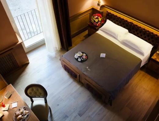 Camera lussuosa del Le Club Boutique Hotel con letto matrimoniale, balcone, colazione servita, bouquet di fiori e arredi eleganti.