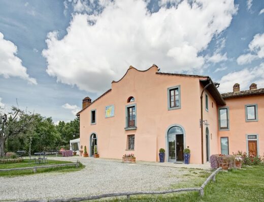 Le Fonti a San Giorgio: Facciata esterna dell'agriturismo toscano con prato, ghiaia e cielo nuvoloso. Ideale per vacanze e weekend in Toscana.