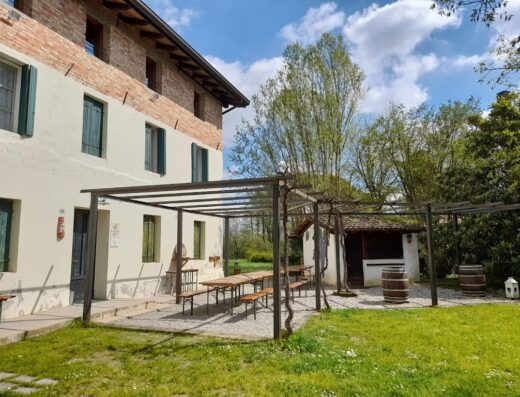 Le Fornaci del Zarnic Agriturismo: Esterno della fattoria didattica con pergola, tavoli rustici, edificio in pietra e barili decorativi.